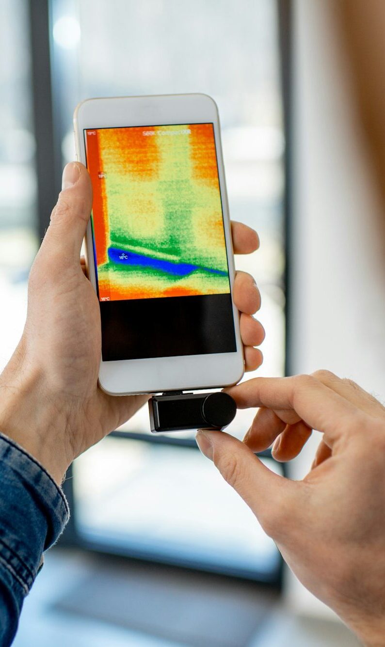 Man checking the house heat loss with thermovision camera indoors